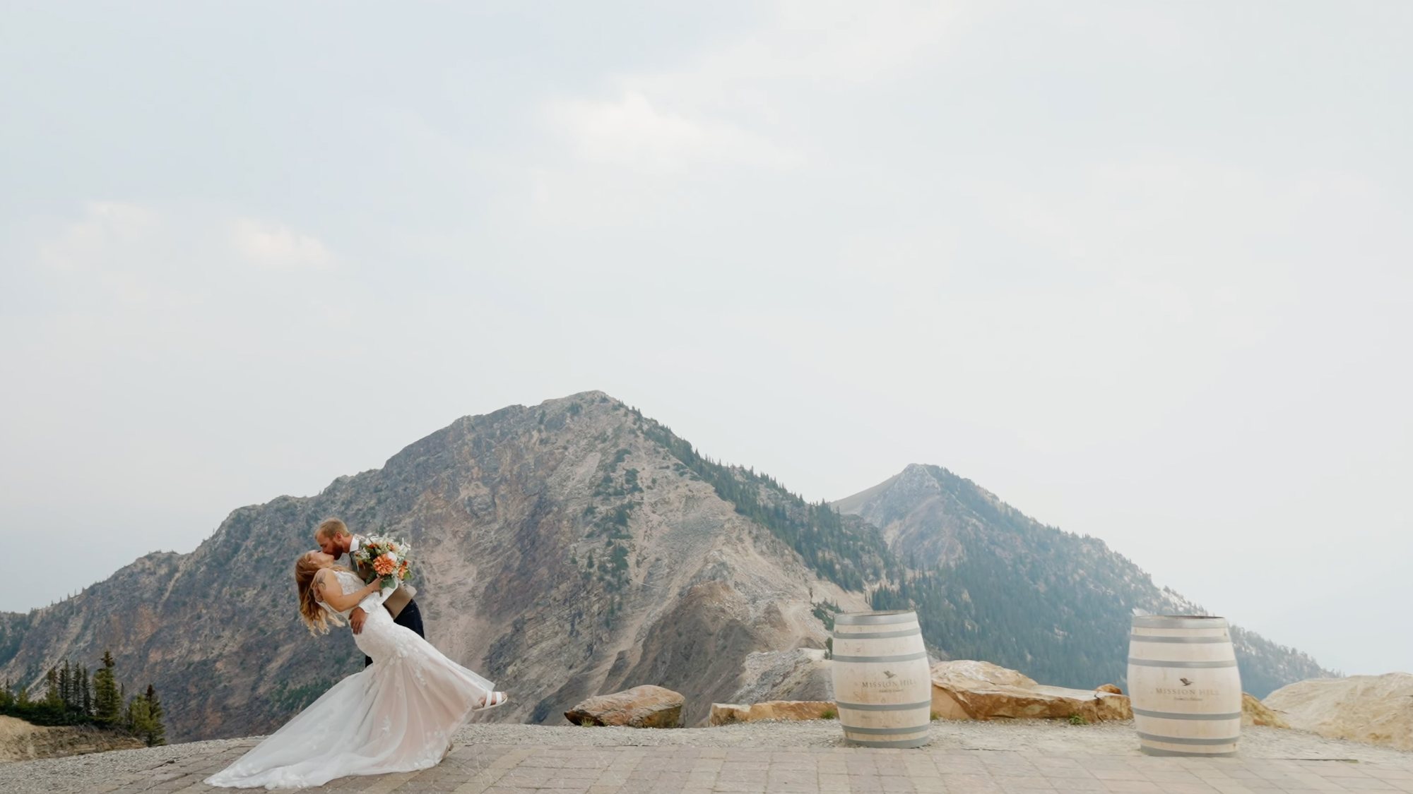 Bride alone on a stone terrace with a mountain range rising behind her
